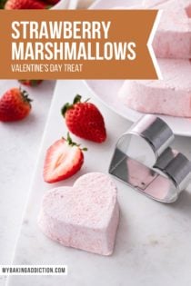 Heart-shaped strawberry marshmallow next to a metal heart cookie cutter on a white board. Text overlay includes recipe name.