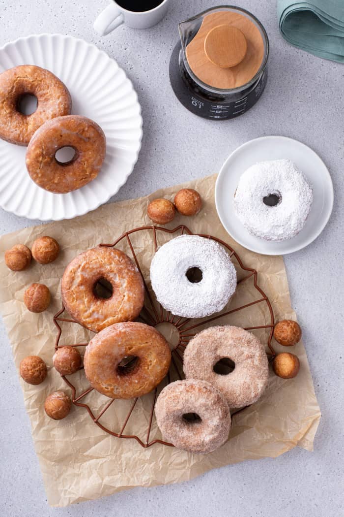 Assorted cake donuts, covered in powdered sugar, cinnamon sugar, and vanilla glaze, arranged on a wire rack.