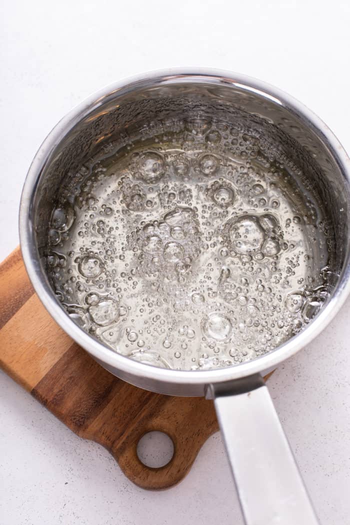 Boiling corn syrup mixture set on a wooden trivet.