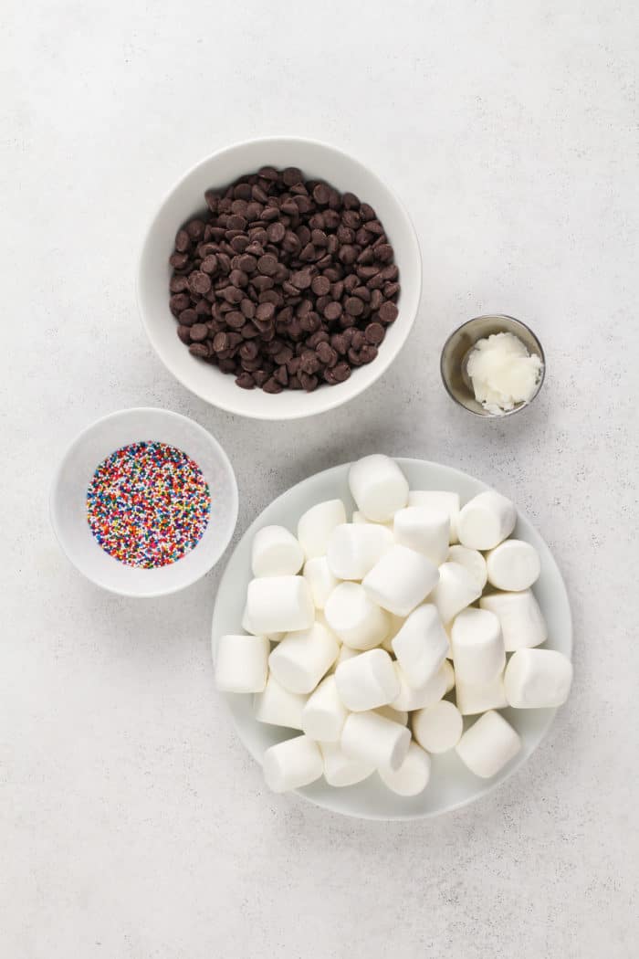 Ingredients for chocolate-covered marshmallows on a light-colored countertop.