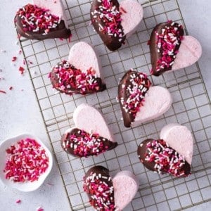Overhead view of strawberry marshmallows cut into hearts and halfway dipped in chocolate.