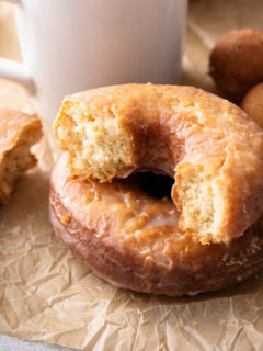 Halved cake donut set next to a cup of coffee.