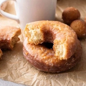 Halved cake donut set next to a cup of coffee.