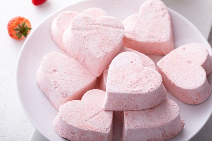 White plate filled with heart-shaped strawberry marshmallows.