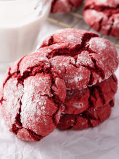 Three stacked red velvet crinkle cookies with a fourth cookie leaning against the stack.