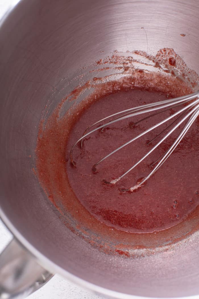 Strawberry powder, water, and gelatin mixed in a metal bowl.