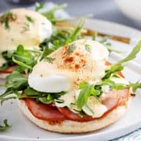 Close up of eggs benedict on a white plate.