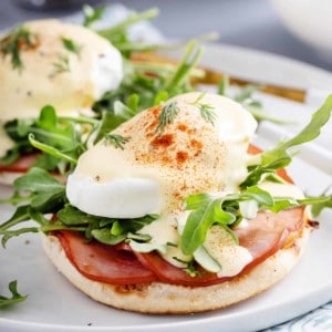 Close up of eggs benedict on a white plate.