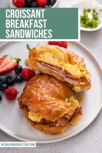 White plate topped with a halved croissant breakfast sandwich and fresh berries. Text overlay includes recipe name.