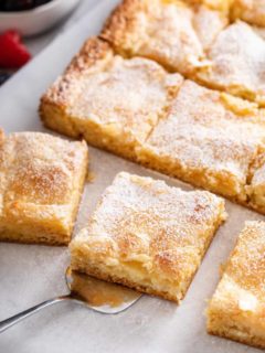 Sliced gooey butter cake, with a cake server about to lift up a slice of the cake.