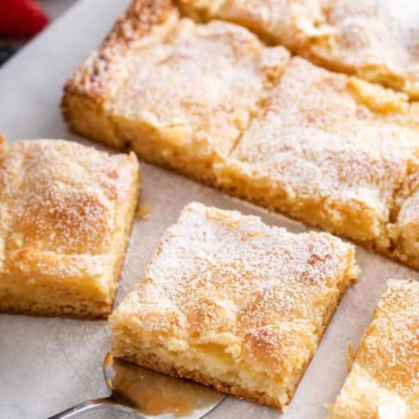 Sliced gooey butter cake, with a cake server about to lift up a slice of the cake.