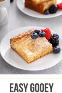 Slice of gooey butter cake on a white plate, garnished with fresh berries. Text overlay includes recipe name.