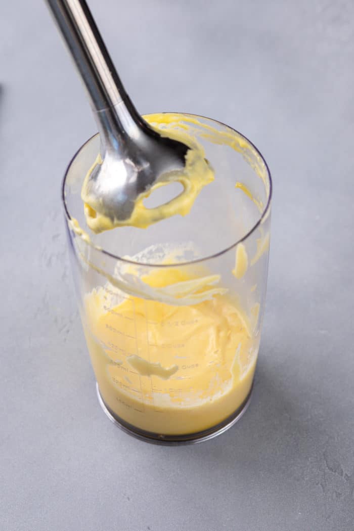 Freshly made hollandaise sauce in a cup with an immersion blender.