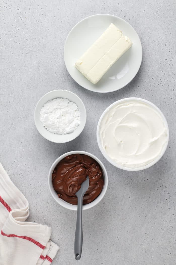 Ingredients for nutella fruit dip arranged on a gray countertop.