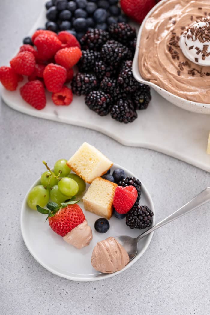 White plate filled with cubes of pound cake, fresh fruit, and a dollop of nutella fruit dip.