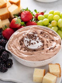 Bowl of nutella fruit dip on a platter with fresh fruit and cubes of pound cake.