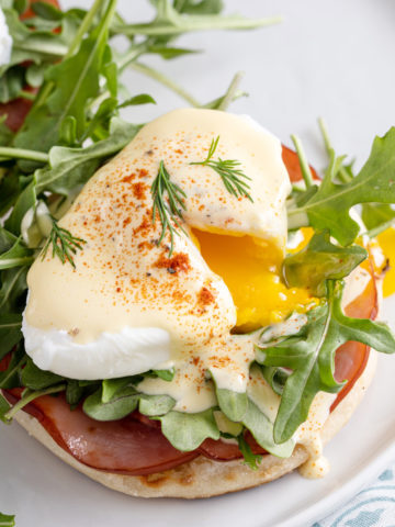 Runny poached egg on eggs benedict.