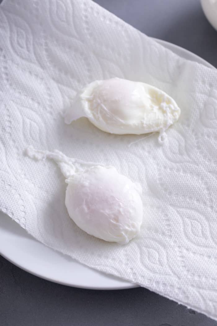 Two poached eggs resting on a paper towel.