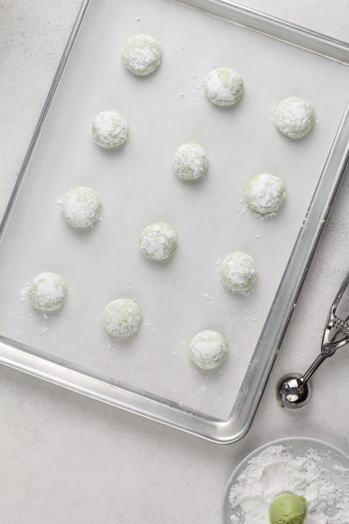 Unbaked st patrick's day crinkle cookies on a parchment-lined baking sheet, ready to go in the oven.