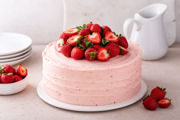 Strawberry layer cake frosted with strawberry frosting and topped with fresh strawberries.