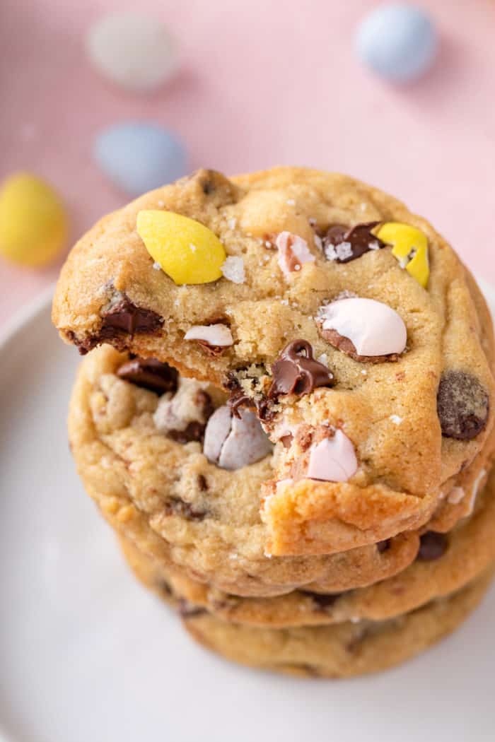 Cadbury egg cookies stacked on a white plate. A bite has been taken from the top cookie.