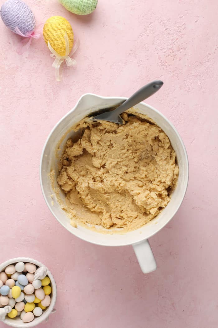 Cookie dough base in a white mixing bowl, waiting for chocolate chips to be added to it.