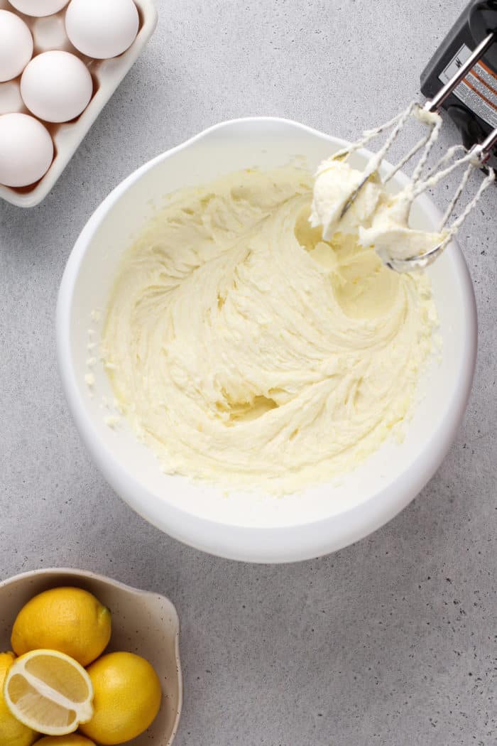Creamed butter, sugar, and cream cheese in a white mixing bowl.
