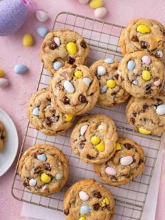 Cadbury egg cookies scattered on a wire cooling rack on top of a piece of parchment paper.