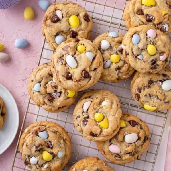 Cadbury egg cookies scattered on a wire cooling rack on top of a piece of parchment paper.