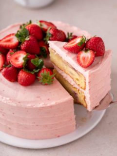 Cake server lifting up a slice of cake from a strawberry layer cake.