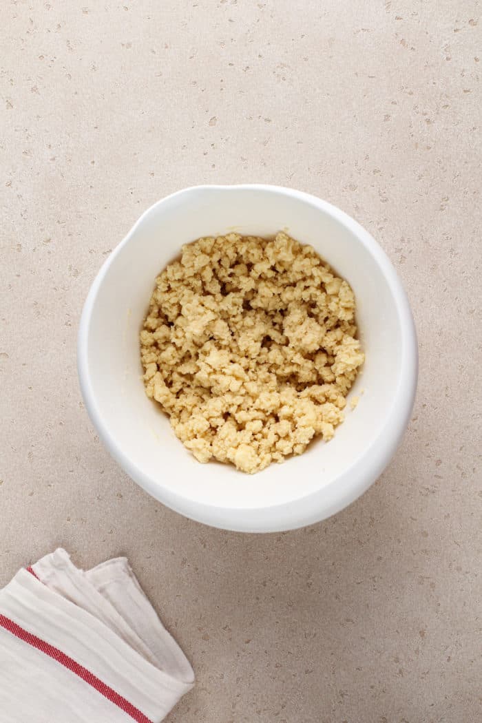Crumbly crust mixture for nana's easy cheesecake in a white mixing bowl.