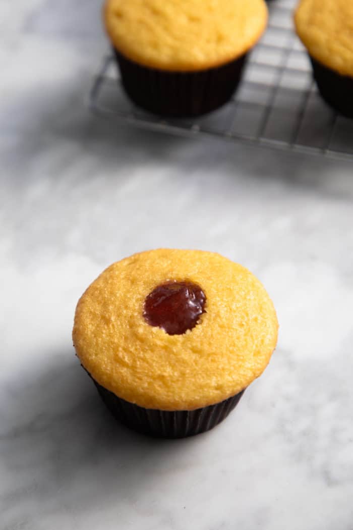 Cupcake that has been hollowed with an apple corer filled with strawberry jam.
