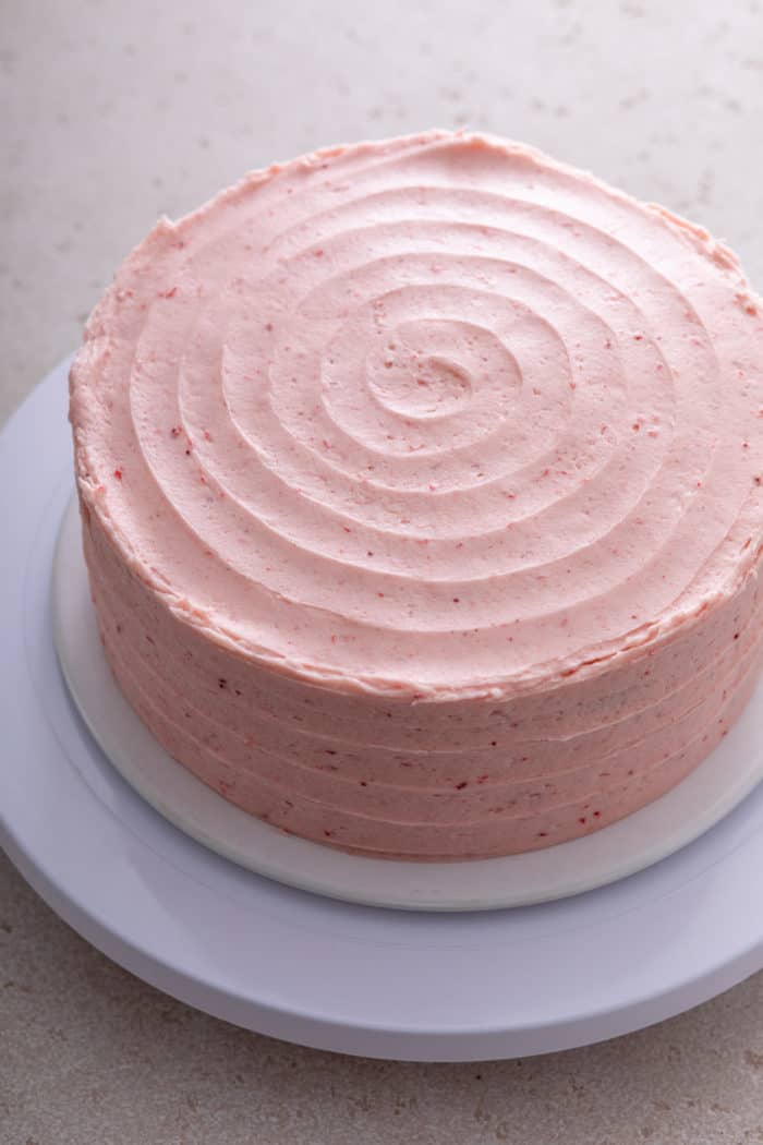 Frosting spread onto a strawberry layer cake.
