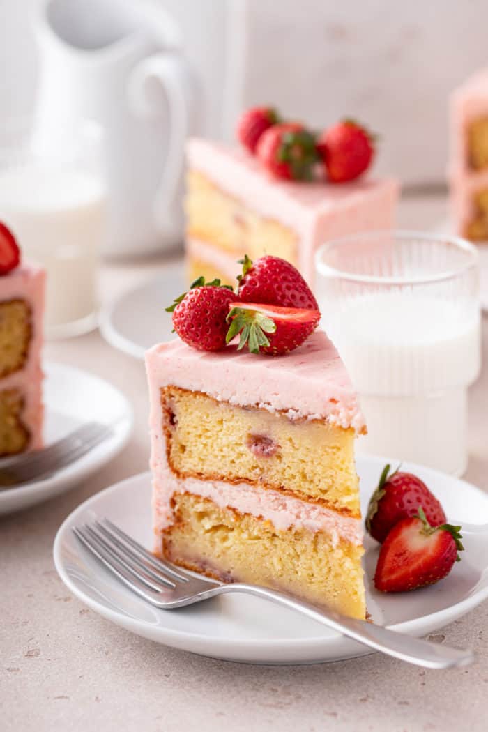 Close up of a slice of strawberry layer cake on a white plate.