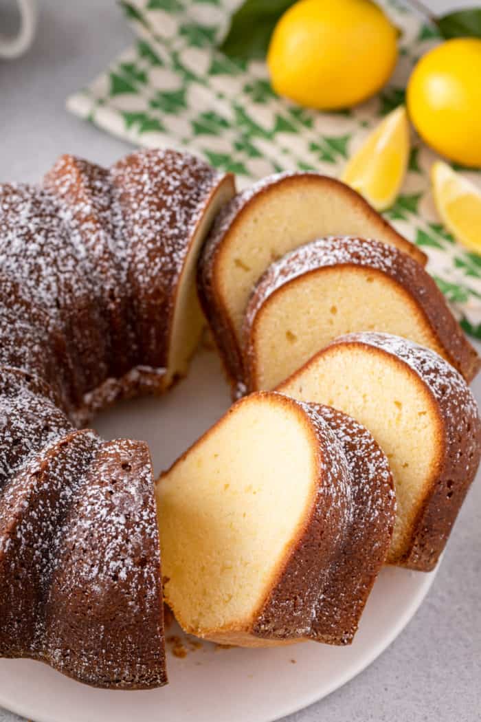 Sliced lemon cream cheese pound cake set on a white cake plate.