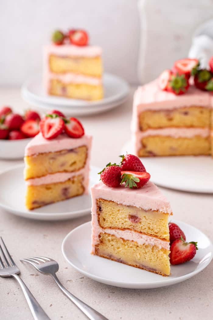 Several plated slices of strawberry layer cake, each topped with fresh strawberries.