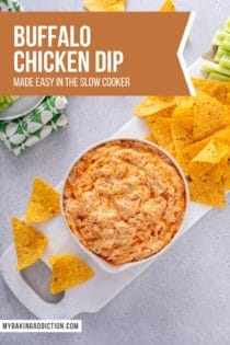 Overhead view of a bowl of buffalo chicken dip on a white cutting board, surrounded by tortilla chips. Text overlay includes recipe name.