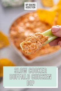 Hand holding up a celery stick with slow cooker buffalo chicken dip on it. Text overlay includes recipe name.