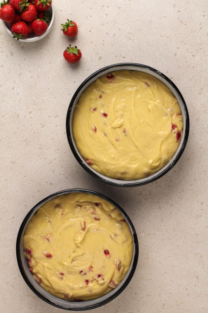 Strawberry cake batter divided into two cake pans, ready to go in the oven.