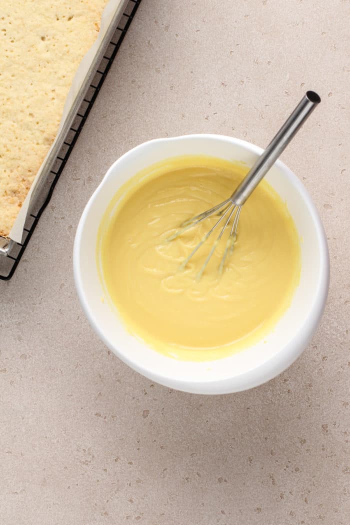 Filling for banana cream bars being whisked in a white mixing bowl.