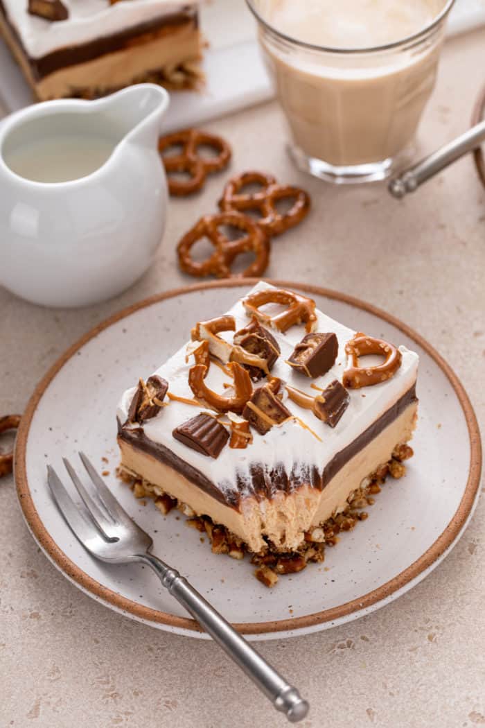 Piece of peanut butter pretzel dessert on a plate with a bite taken from the corner of it.