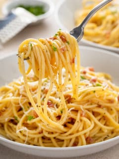 Fork picking up a bite of pasta carbonara.