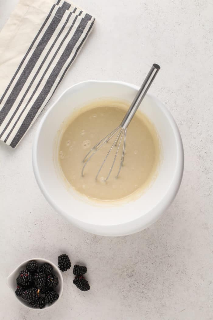 Batter for easy blackberry cobbler being whisked together in a white mixing bowl.