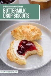 Bite taken from a buttermilk drop biscuit that has been split in half and topped with butter and berry jam. Text overlay includes recipe name.