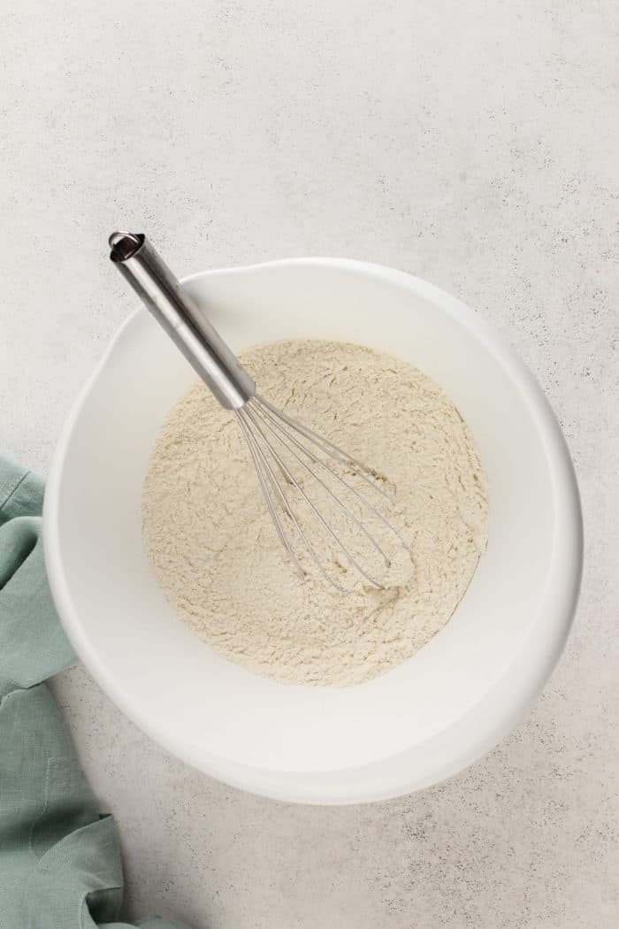 Dry ingredients for buttermilk pancakes being whisked in a white mixing bowl.