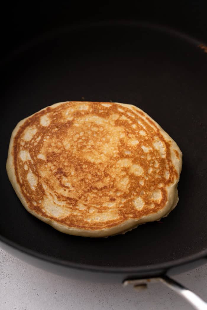 Cooked buttermilk pancake in a black skillet.