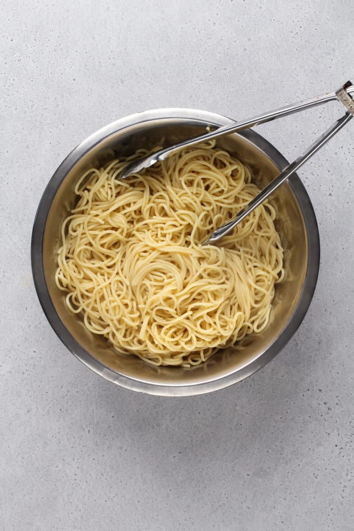 Cooked spaghetti in a metal mixing bowl.