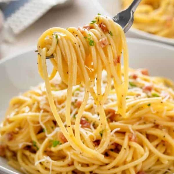 Fork picking up a bite of pasta carbonara.