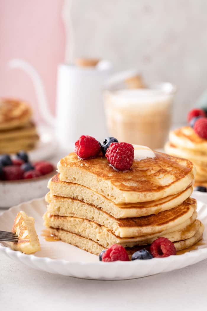 Stack of buttermilk pancakes with a large bite cut from one of the edges.