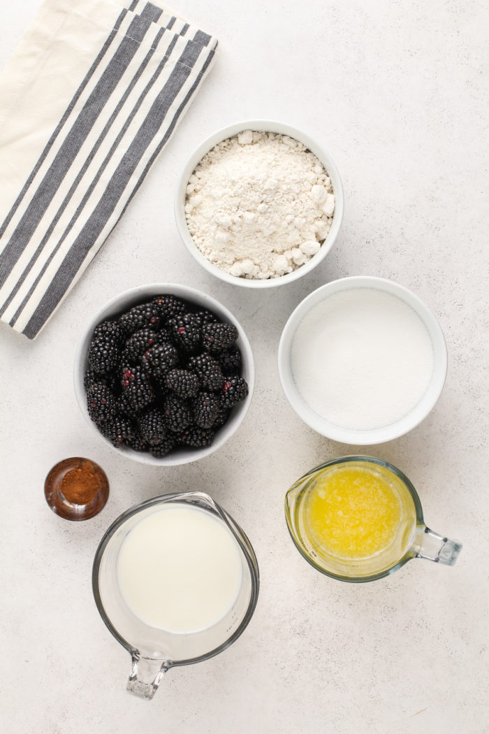 Ingredients for blackberry cobbler arranged on a white countertop.